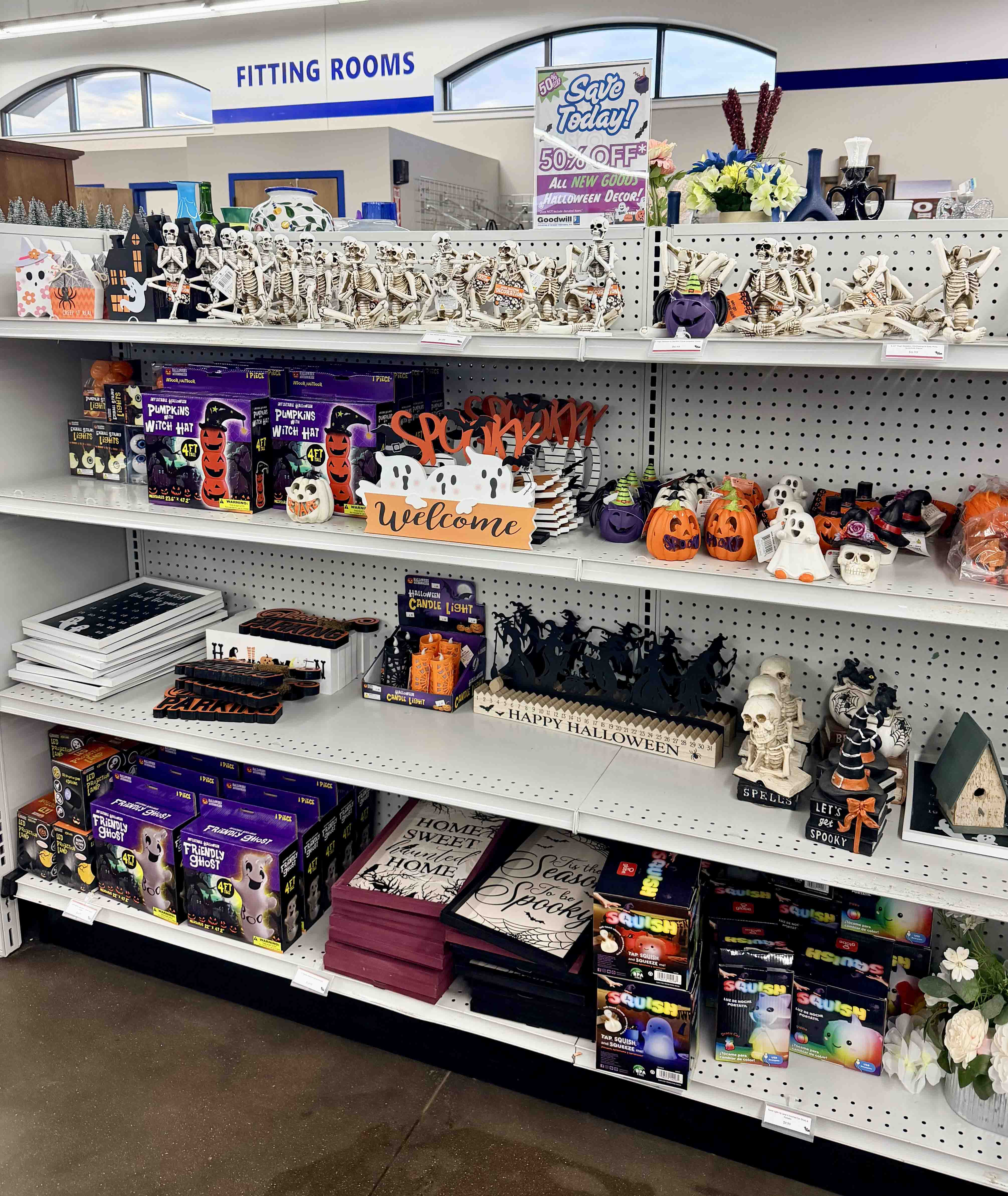 Four-tiered shelf in a Goodwill store filled with various Halloween decorations.