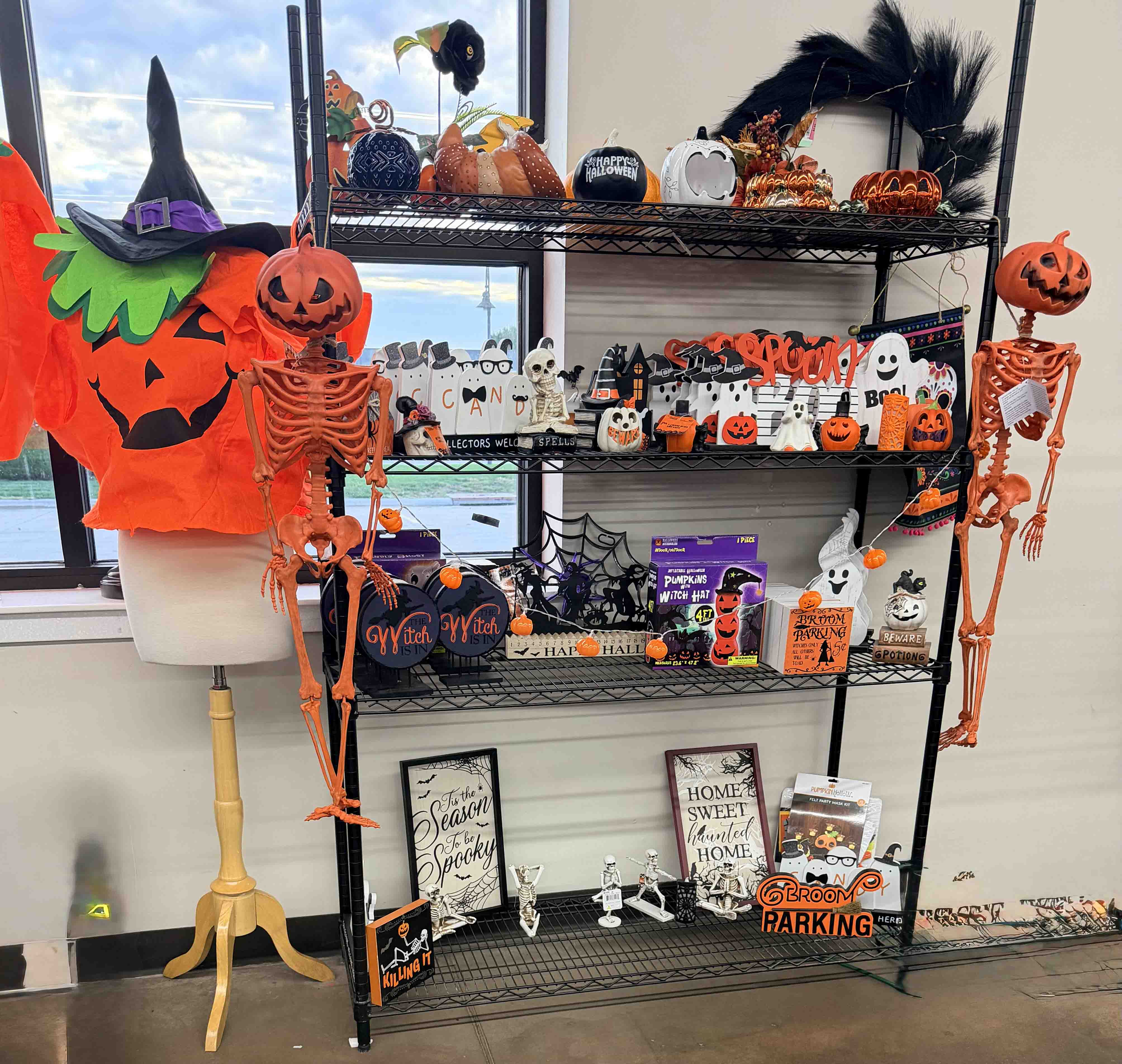 Four tierd shelf in a Goodwill store full of various Halloween decorations.