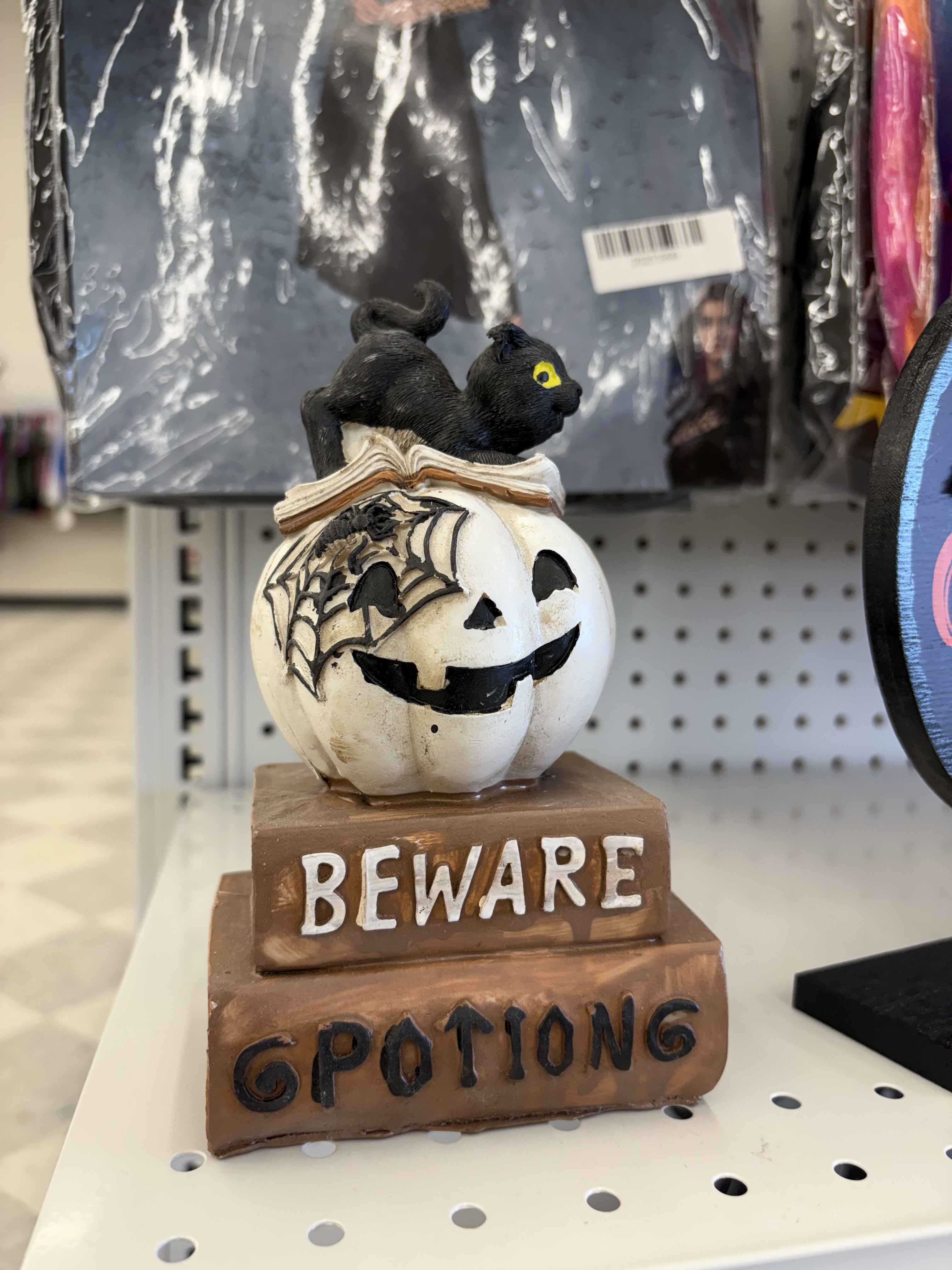 Decoration of a black cat on top of a jack-o-latern and potions book.